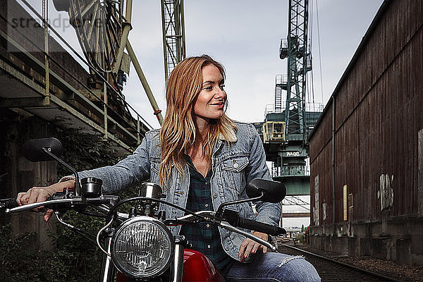 Porträt einer lächelnden jungen Frau auf Motorrad