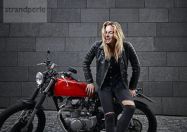 Porträt einer lachenden jungen Frau mit Motorrad