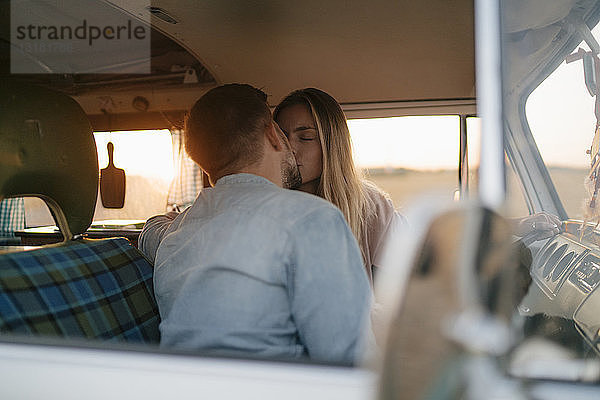 Junges Paar küsst sich bei Sonnenuntergang im Wohnmobil