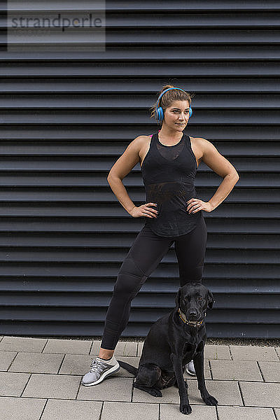Porträt einer jungen Frau mit Kopfhörer und Hund im Freien