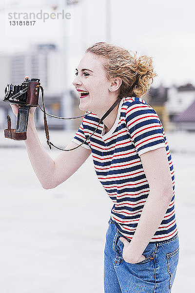 Porträt einer lachenden jungen Frau mit Oldtimer-Kamera