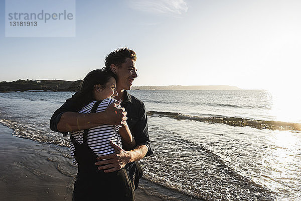 Frankreich  Bretagne  glückliches junges Paar umarmt sich bei Sonnenuntergang am Strand