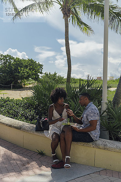 USA  Florida  Miami Beach  junges Paar mit Salat und Handy in einem Park