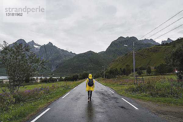 Norwegen  Lappland  Vesteralen-Inseln  Junger Mann geht auf leerer Straße  Rückansicht