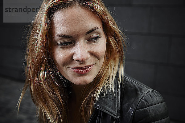 Porträt einer lächelnden jungen Frau in Biker-Jacke