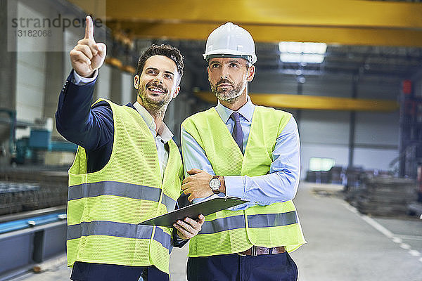 Zwei Manager in Arbeitsschutzkleidung im Gespräch in der Fabrik