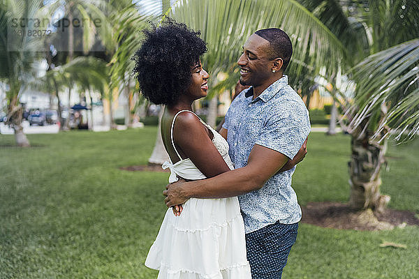 USA  Florida  Miami Beach  glückliches junges Paar umarmt sich im Sommer in einem Park