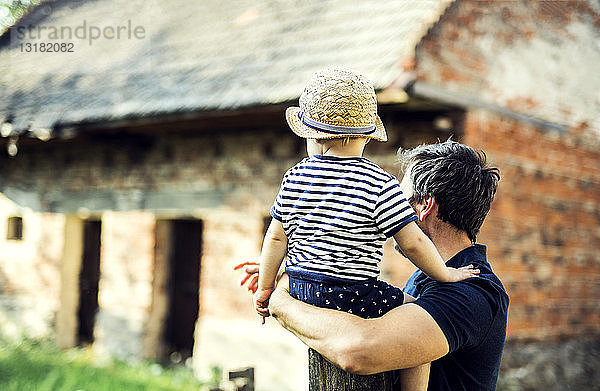 Rückenansicht von Vater und kleinem Sohn  die etwas im Freien beobachten