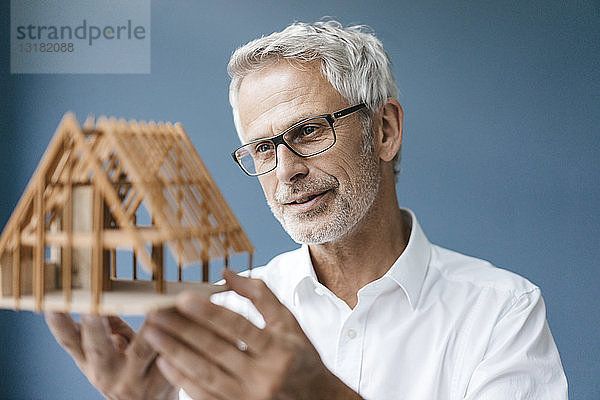 Erfolgreicher Architekt betrachtet Modell eines Hauses
