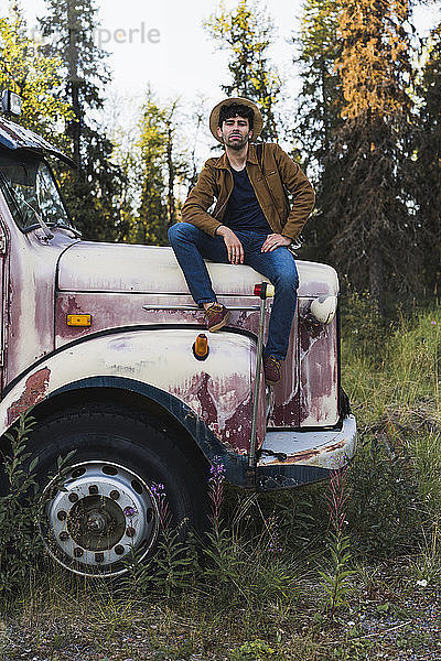 Cooler junger Mann sitzt auf einem kaputten Lastwagen