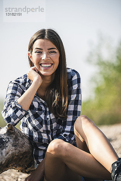 Porträt einer glücklichen jungen Frau  die im Freien sitzt