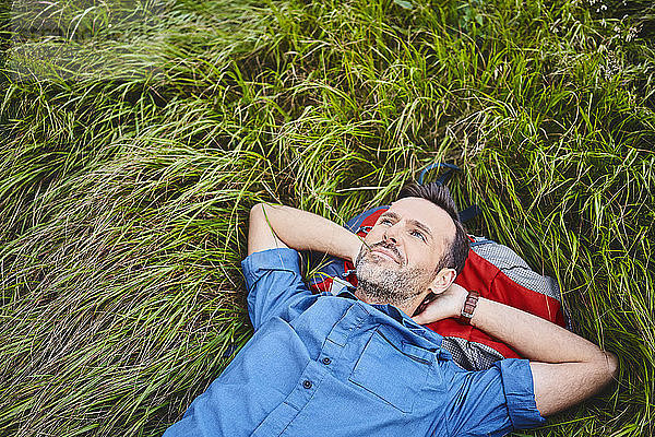 Entspannter Mann liegt im Gras und genießt Wanderung
