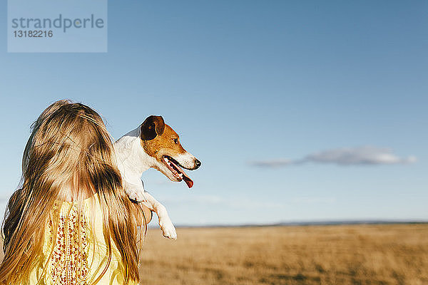 Mädchen hält Hund auf einem Feld