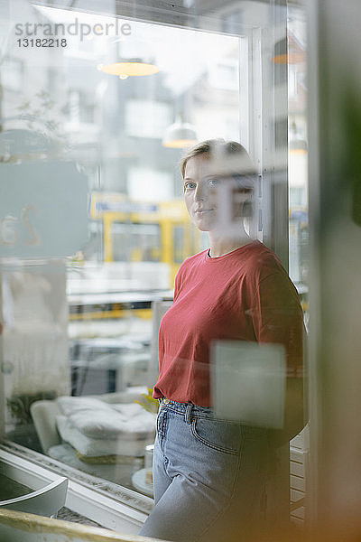 Porträt einer jungen Frau  die sich in einem Cafe an die französische Tür lehnt