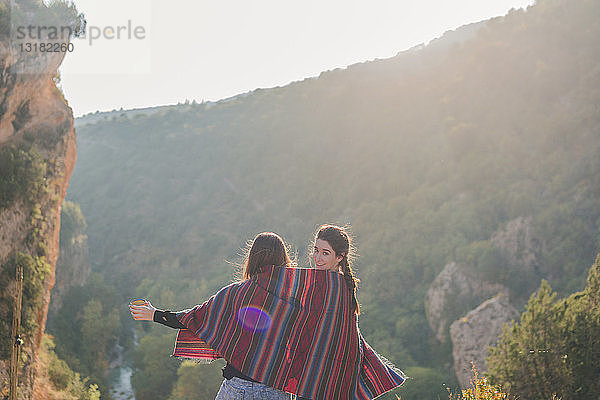 Spanien  Alquezar  Rückansicht von zwei jungen Frauen auf einer Wanderung  die sich eine Decke teilen