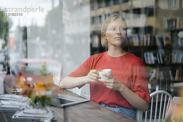 Junge Frau mit Laptop und Kaffeetasse in einem Cafe