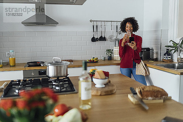 Frau steht in ihrer Küche  nimmt einen Selfie  trinkt Wein