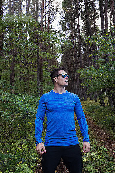 Sportler mit Sonnenbrille im Wald stehend