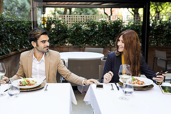 Lächelnde Frau und Mann mit Handy in einem Restaurant