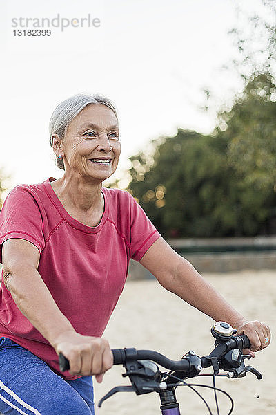 Porträt einer lächelnden älteren Frau beim Fahrradfahren