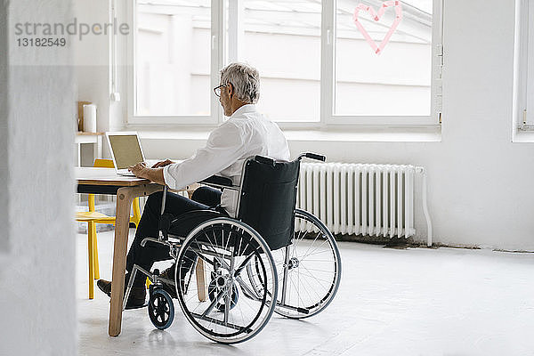 Behinderter Manager im Rollstuhl  der im Büro arbeitet