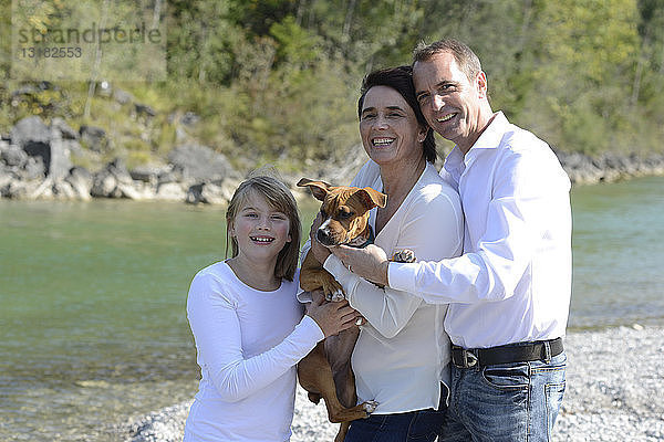 Glückliche Familie mit einem Hund an der Isar  Oberbayern  Deutschland