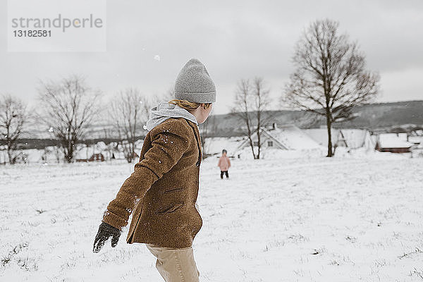 Junge und seine kleine Schwester spielen zusammen in schneebedeckter Landschaft