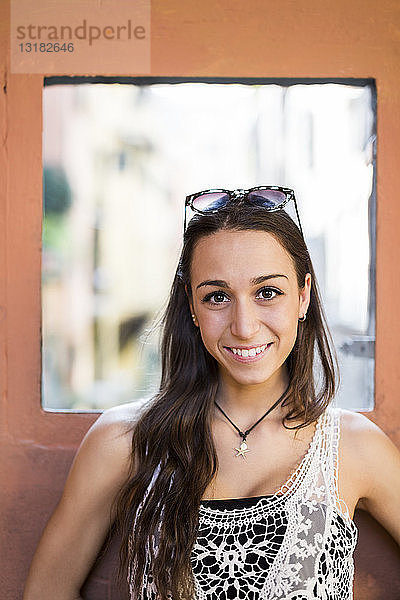 Porträt einer lächelnden jungen Frau mit braunen Haaren und Augen
