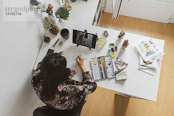 Illustratorin malt am Schreibtisch in einem Atelier mit einem digitalen Tablett  Draufsicht