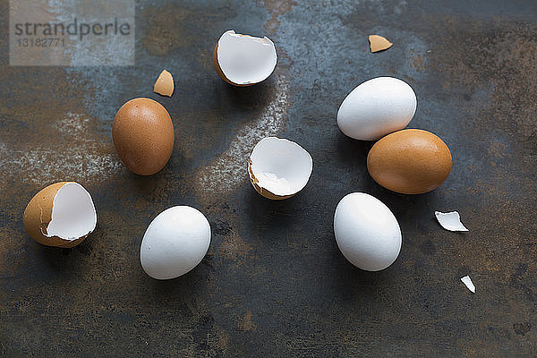 Weiße und braune Eier und Eierschalen auf rostigem Metall