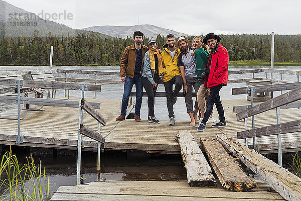 Finnland  Lappland  Porträt von Freunden  die auf einem Steg an einem See stehen