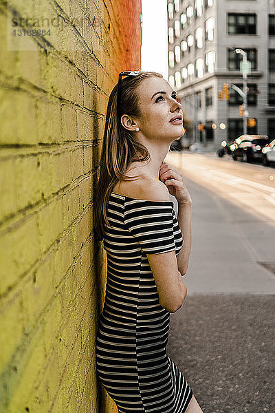 USA  New York  Brooklyn  Dumbo  junge Frau lehnt an der gelben Wand und schaut auf