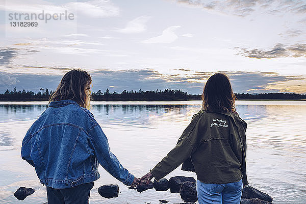 Freundinnen betrachten den Inari-See  Finnland  und halten sich an den Händen