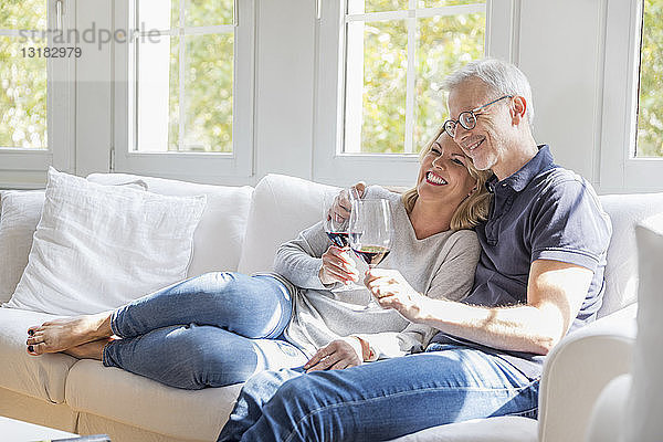 Reifes Paar entspannt sich auf der Couch bei Rotwein und hat Spaß