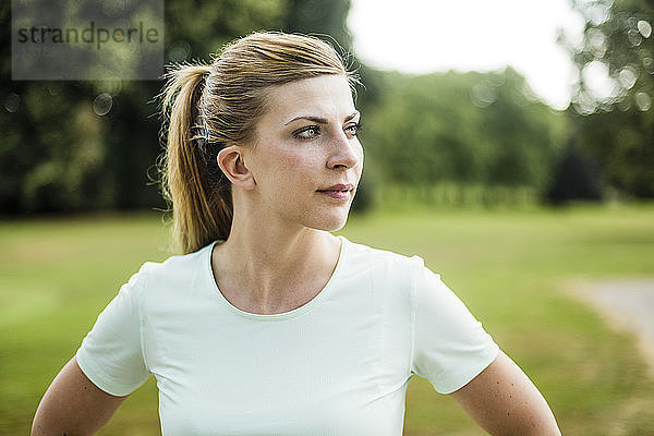 Porträt einer sportlichen jungen Frau in einem Park mit Blick zur Seite