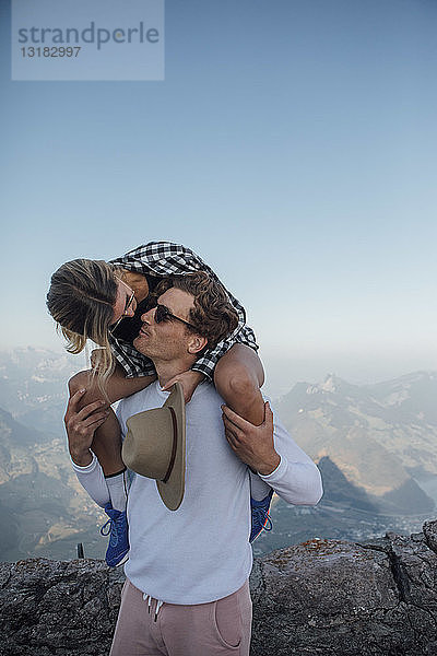 Schweiz  Grosser Mythen  junger Mann  der seine Freundin auf die Schultern küsst