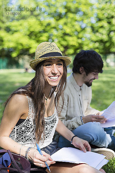 Porträt eines glücklichen jungen Studenten  der im Park sitzt