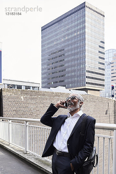 Großbritannien  London  lachender Senior-Geschäftsmann am Telefon im Freien
