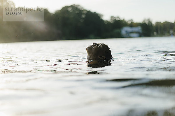 Frau schwimmt bei Sonnenuntergang in einem See