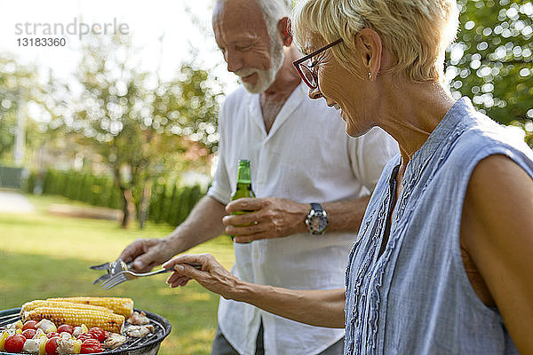 Älteres Ehepaar beim Grillen im Garten