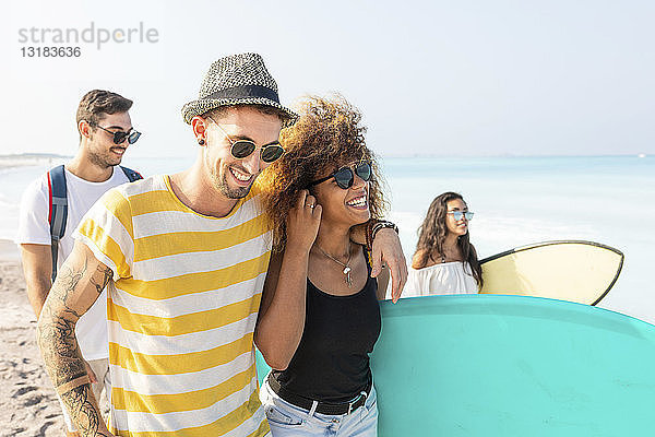 Gruppe von Freunden  die mit Surfbrettern am Strand spazieren gehen