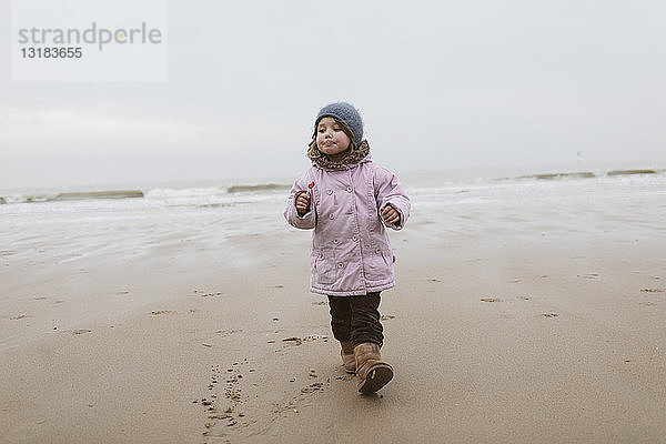 Deutschland  Nordseeküste  kleines Mädchen mit Lolly  das im Winter am Strand spazieren geht