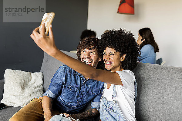 Glückliches Paar  das auf der Couch sitzt und ein Selfie