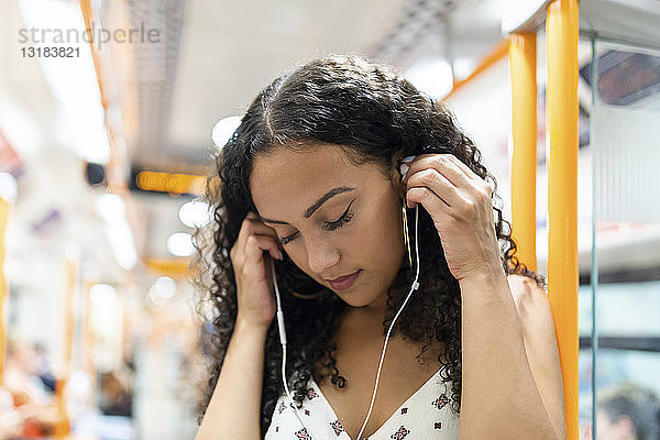 Junge Frau  die in der U-Bahn mit Kopfhörern Musik hört