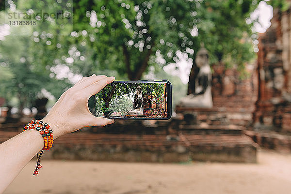 Thailand  Ayutthaya  Frau beim Fotografieren einer Buddhastatue im Wat Mahathat