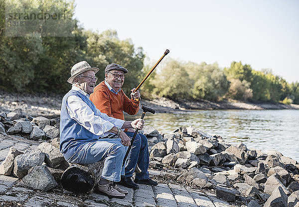Zwei alte Freunde sitzen am Flussufer und amüsieren sich