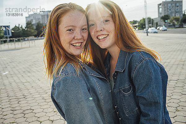 Lächelnde rothaarige Zwillinge in der Stadt  Sonnenlicht
