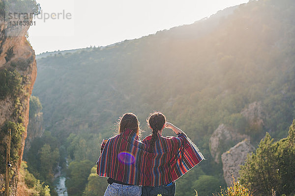 Spanien  Alquezar  Rückansicht von zwei jungen Frauen auf einer Wanderung  die sich eine Decke teilen