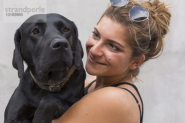 Porträt einer glücklichen jungen Frau mit ihrem schwarzen Hund