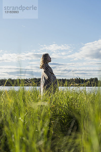 Finnland  Lappland  Frau in eine Decke gewickelt am Seeufer stehend
